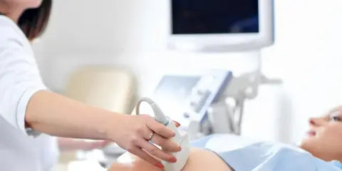 Lekarz wykonuje USG brzucha pacjentki, badając wątrobę pod kątem objawów cholestazy.