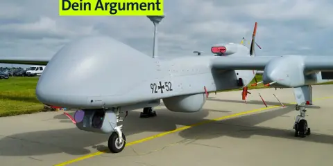 Ein graues UAS, eine Drohne, steht auf dem Flugfeld. Die Aufschrift "Dein Argument" ist über dem Flugzeug angebracht.