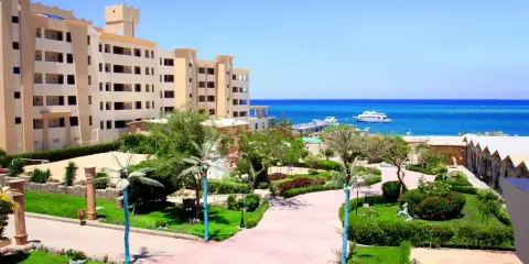 Piękny widok na **King Tut Resort** z basenem, palmami i morzem w tle.