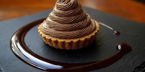 Délicieux Mont Blanc au chocolat, une recette gourmande à essayer. La crème onctueuse forme un cône parfait sur la tartelette.