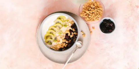 Gesunder Joghurt-Bowl mit Kiwi, Beeren, Nüssen und Granola – perfekt für proteinreiche Mahlzeiten.