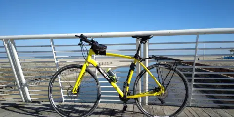 Bicicletta gialla pronta per un giro a Rimini Cattolica, con il mare e la spiaggia sullo sfondo.