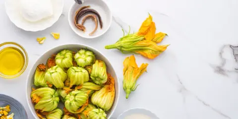 Fiori di zucca freschi, mozzarella, acciughe e olio d'oliva pronti per essere cucinati.