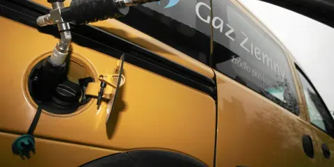 Tankowanie żółtego samochodu gazem ziemnym. Napis na pojeździe: "Gaz Ziemny - źródło przyjazne".