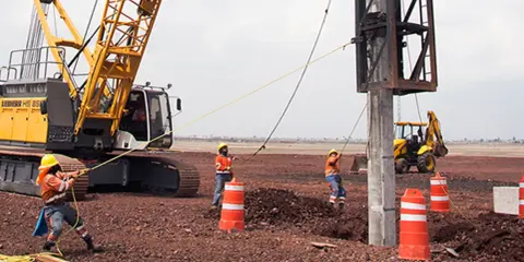 Trabajadores y maquinaria pesada instalan pilotes para cimentaciones profundas en un sitio de construcción.