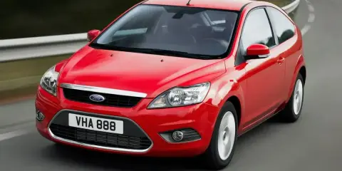 Czerwony Ford Focus MK2 1.6 benzyna w wersji 3-drzwiowej, jadący po zakręcie drogi.