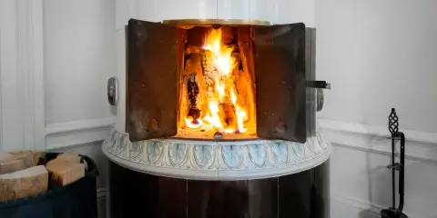 En öppen kamin med flammande ved. Det kan vara farligt att elda i kamin om man inte är försiktig.