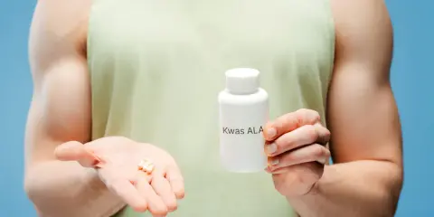 Mężczyzna trzyma buteleczkę z napisem "Kwas ALA" i kilka kapsułek na dłoni. Kwas alfa liponowy na co?