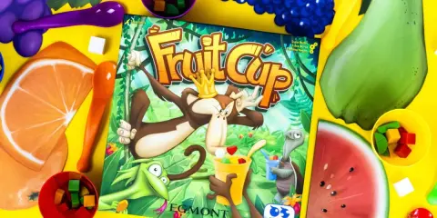Gra Fruit Cup z owocami i kostkami. Małpa w koronie miesza owocowy deser.