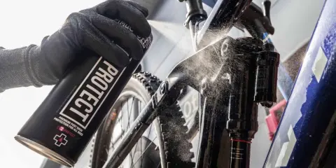 Rękawica z puszką "PROTECT" rozpyla środek na ramę roweru elektrycznego, pokazując, jak myć rower elektryczny.