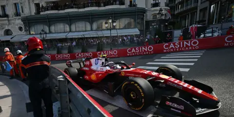 Lewis Hamilton im Ferrari-Boliden rast durch Monaco. Zuschauer säumen die Strecke, die Casino-Werbung blinkt.