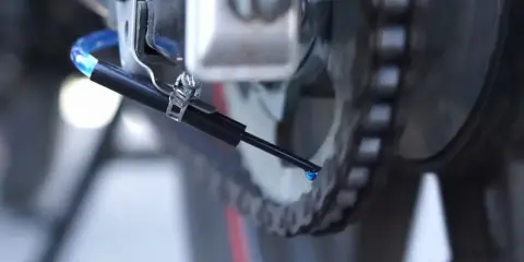 Kropla oleju spada z dyszy systemu automatycznego smarowania łańcucha na ogniwa napędu.