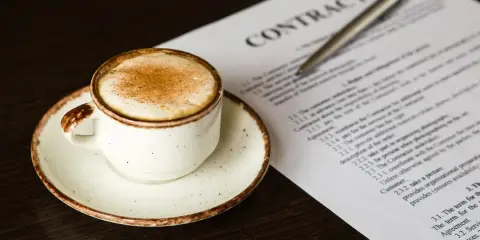 Taza de café con canela junto a un contrato, quizás revisando el artículo 27 de la LAU.