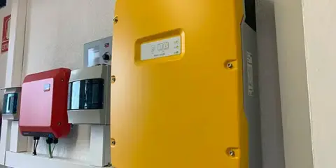 Gul SMA solcellsväxelriktare, en röd enhet och en grå enhet monterade på en vägg. En solig dag för att maximera din sunny tripower.