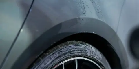 Krople wody na lakierze samochodu i piana na oponie. Szukasz sposobu, czym odtłuścić lakier domowe sposoby?