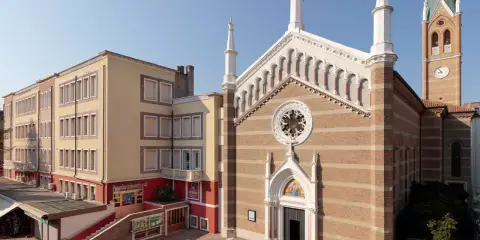 Facciata di una chiesa a Rimini con campanile e edificio adiacente.