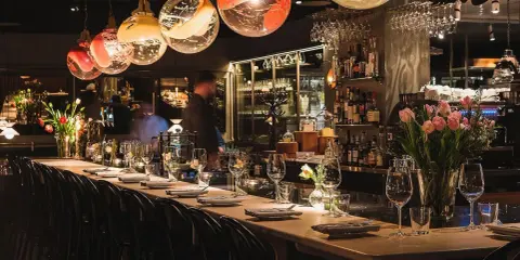 Elegant bar i en michelin restaurang Stockholm. Vackra glaslampor, blommor och uppdukade bord skapar en lyxig atmosfär.