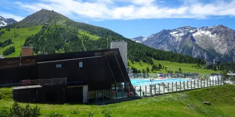 Una splendida piscina in montagna in Piemonte, con vista su verdi colline e cime innevate.