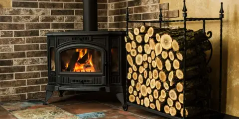 Poêle à bois crépitant, prêt pour un rendement optimal. Bûches bien rangées à côté, promettant une chaleur réconfortante.