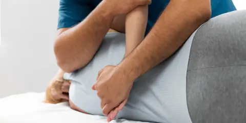 Fizjoterapeuta wykonuje masaż pleców. Czy fizjoterapia może zaszkodzić? Zawsze wybieraj doświadczonych specjalistów.