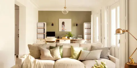 Ideas pintar salón en dos colores: pared verde texturizada y paredes blancas luminosas. Sofá beige, mesa de centro rústica, plantas y arte.
