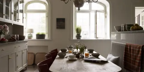 Rustik matplats med träbord, röda stolar och en bänk. Vackra fönster och skåp ger inspiration för inredningstips.