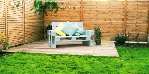 Ein gemütliches Palettensofa bauen: Ein hellblaues Sofa aus Paletten mit Kissen steht auf einer Holzterrasse im Garten.