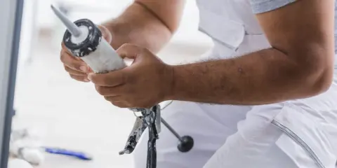Un bricoleur prépare son pistolet à mastic pour une application. Il tient le tube de mastic Sika, prêt à l'emploi.