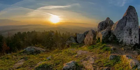 Zachód słońca nad skalistym wzgórzem, z którego roztacza się widok na łagodne wzgórza i lasy. To krajobraz, który przypomina, że nawet najniższe góry w Polsce potrafią zachwycić.
