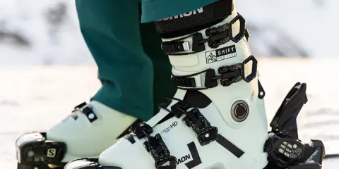 Jasne buty narciarskie Salomon z czarnymi klamrami na nartach.