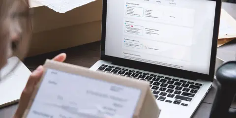 Osoba przygotowuje zwrot kurierem, wypełniając formularz na laptopie. Na ekranie widoczne są dane nadawcy i odbiorcy.