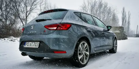 Szary Seat Leon FR w zimowej scenerii, pokryty śniegiem.