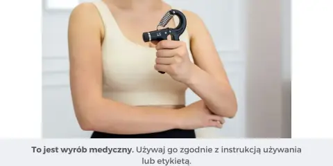 Kobieta ćwiczy chwyt dłoni przyrządem do kinezyterapii, wzmacniając mięśnie przedramienia.