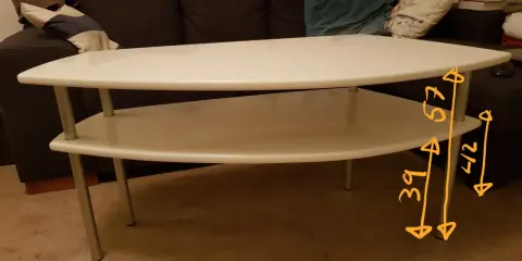 Vitt, tvådelat, högre soffbord med måtten 39x42x57 cm. Bakom syns en mörk soffa med kuddar.