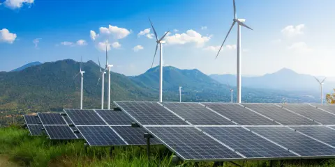 Panele słoneczne i wiatraki na tle gór i błękitnego nieba. To przyszłość, którą wspiera program Energia Plus.