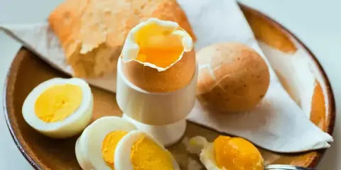 Jajka na miękko i pieczywo na talerzu.
