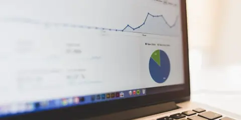 Analiza ankiety na ekranie laptopa: wykres liniowy i kołowy pokazują dane.