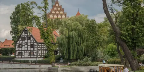 Urokliwy zakątek kujawsko pomorskie atrakcje: zabytkowa zabudowa, malownicza rzeka i łódź spacerowa.