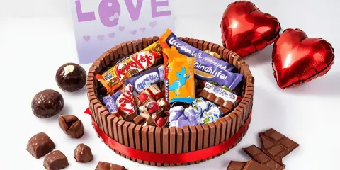 Pastel de xuxes con forma de tarta, decorado con chocolates y globos en forma de corazón. ¡Un regalo perfecto para San Valentín!