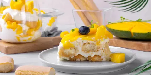 Un délicieux tiramisu mangue, garni de fruits frais et de biscuits à la cuillère. Une touche tropicale pour un dessert rafraîchissant.