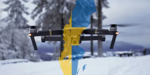 Eine Drohne mit der schwedischen Flagge fliegt über eine verschneite Landschaft.