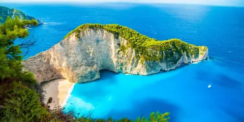 Widok na Navagio Beach, jedną z najpiękniejszych greckich atrakcji. Białe klify, turkusowa woda i zielona roślinność tworzą rajski krajobraz.