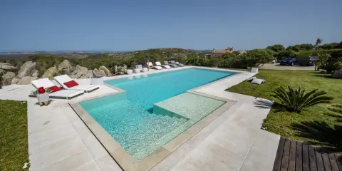 Lussuosa piscina in Sardegna, con vista mare e colline. Ideale per rilassarsi dopo un viaggio in traghetto.