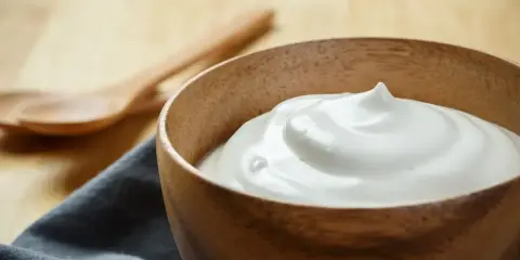 Una ciotola di legno contiene una soffice crema al latte, pronta per essere gustata.