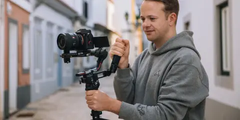 Mężczyzna trzyma profesjonalny aparat do nagrywania na stabilizatorze, gotowy do uchwycenia dynamicznych ujęć na ulicy.