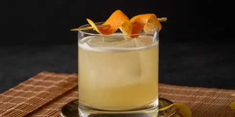Ein erfrischender Cocktail mit Eis, garniert mit Orangenschale. Für die Süße wurde Zuckersirup verwendet, was ist Zuckersirup? Eine einfache Mischung aus Zucker und Wasser.