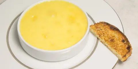 Crème onctueuse à la noix de coco, servie dans un bol blanc avec une tranche de pain grillé.
