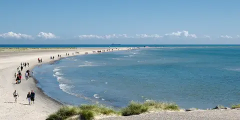 En vacker strandpromenad vid Skagen, med folk som njuter av solen och havet. En perfekt resa till Skagen.