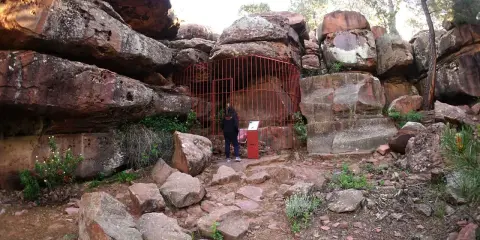 Persona observa pinturas rupestres albarracín, protegidas por una valla roja.