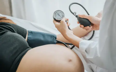 Lekarz mierzy ciśnienie w ciąży u ciężarnej kobiety. Monitorowanie ciśnienia jest kluczowe dla zdrowia mamy i dziecka.